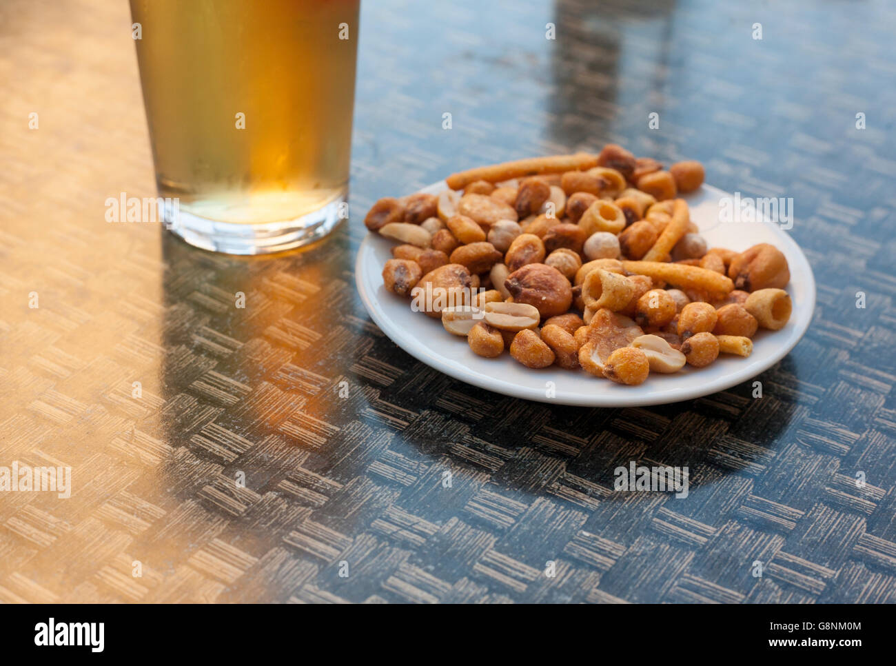 Vetro freddo di birra sulla terrazza con tavolo snack di frutta secca e noci Foto Stock