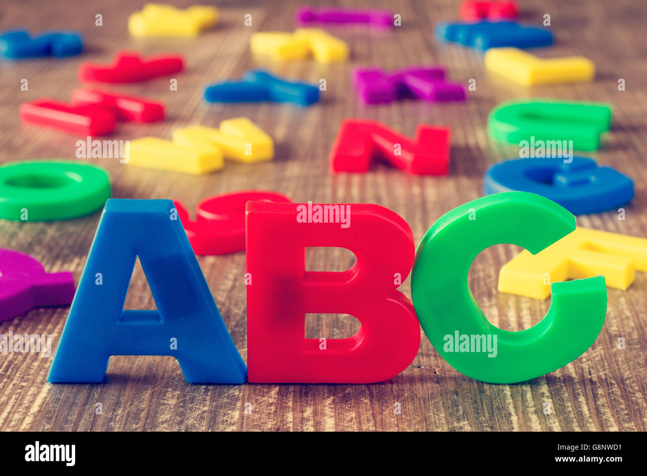 ABC di ortografia e pila di plastica colorata lettere sullo sfondo di legno Foto Stock