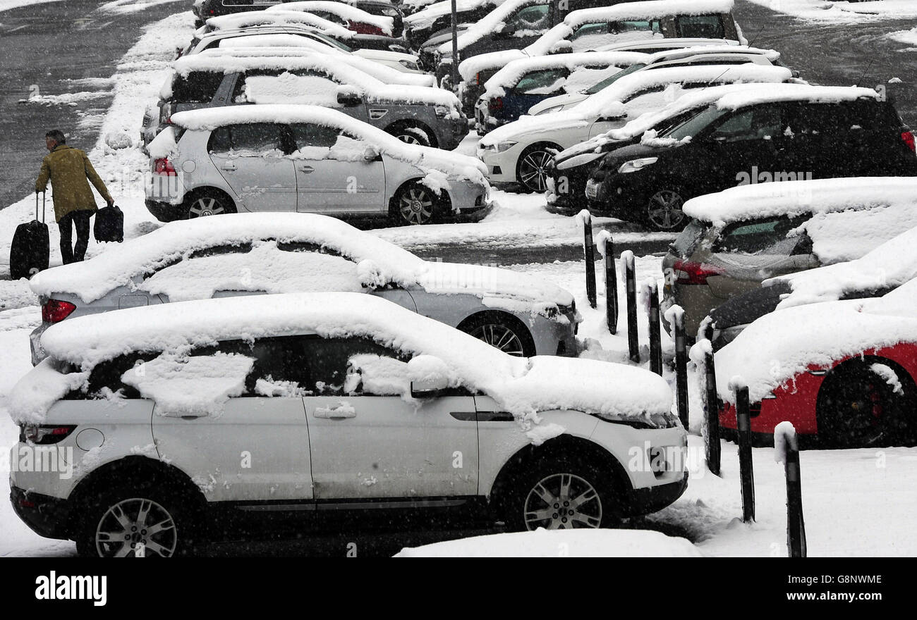 Un passeggero passa attraverso la neve presso il parcheggio dell'aeroporto Leeds Bradford, che è stato costretto a chiudere mentre gli equipaggi hanno lavorato per liberare la pista, Come parti del Regno Unito svegliato fino a quasi quattro pollici di neve il Venerdì mattina, come marzo continua a sentirsi più come l'inverno che la primavera. Foto Stock