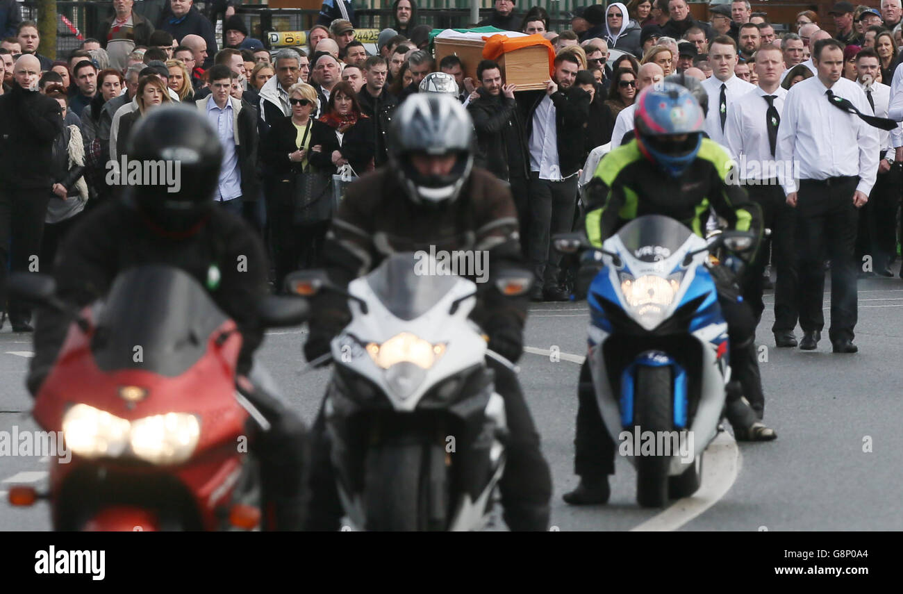 Una guardia d'onore delle motociclette scalda i loro motori come bara del repubblicano dissidente Vincent Ryan è portato nella Chiesa della Santissima Trinità a Donaghmede, Dublino, per la sua Messa funeraria. Foto Stock