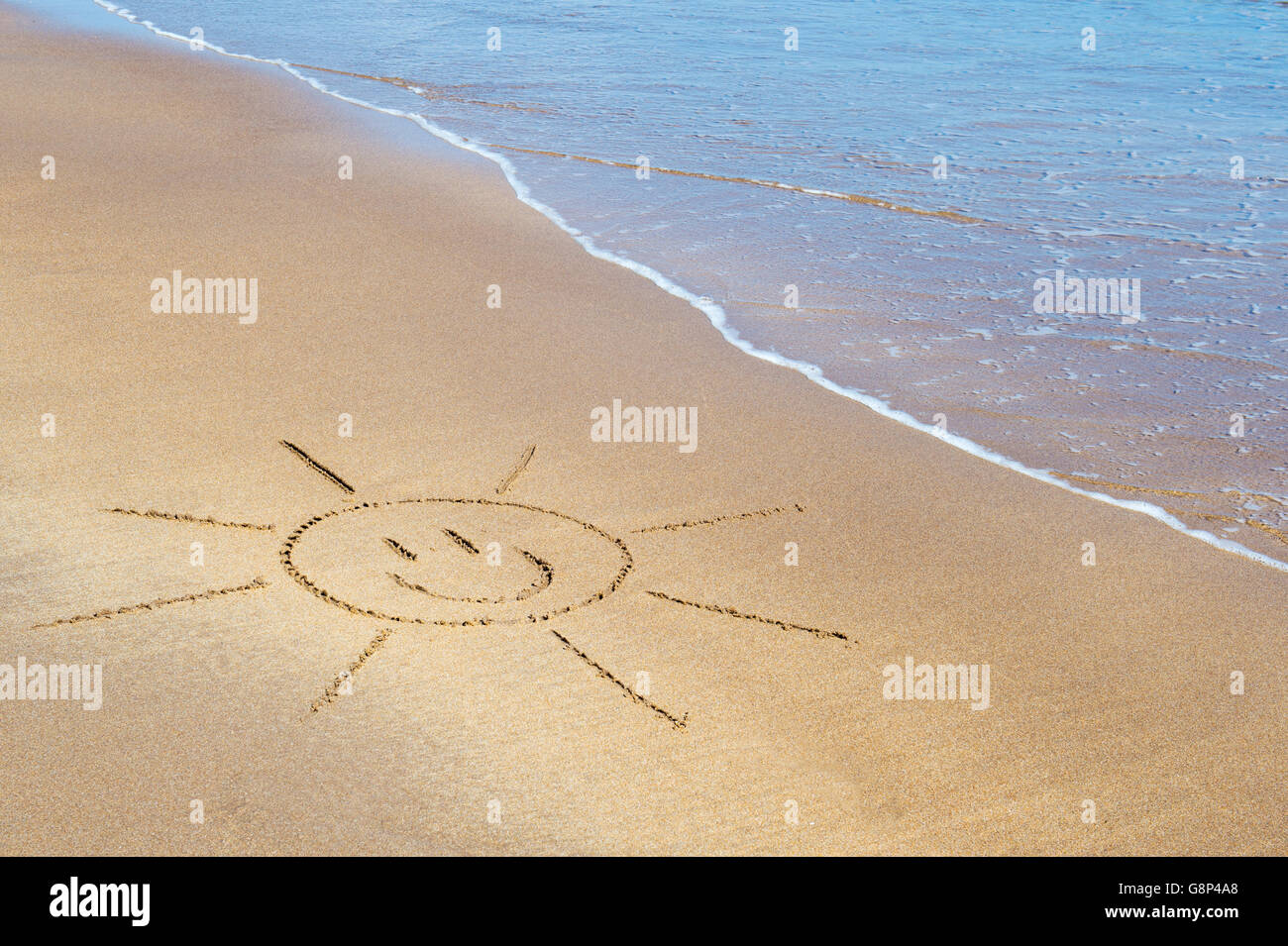 Smiley face sun disegno su una spiaggia. Regno Unito Foto Stock