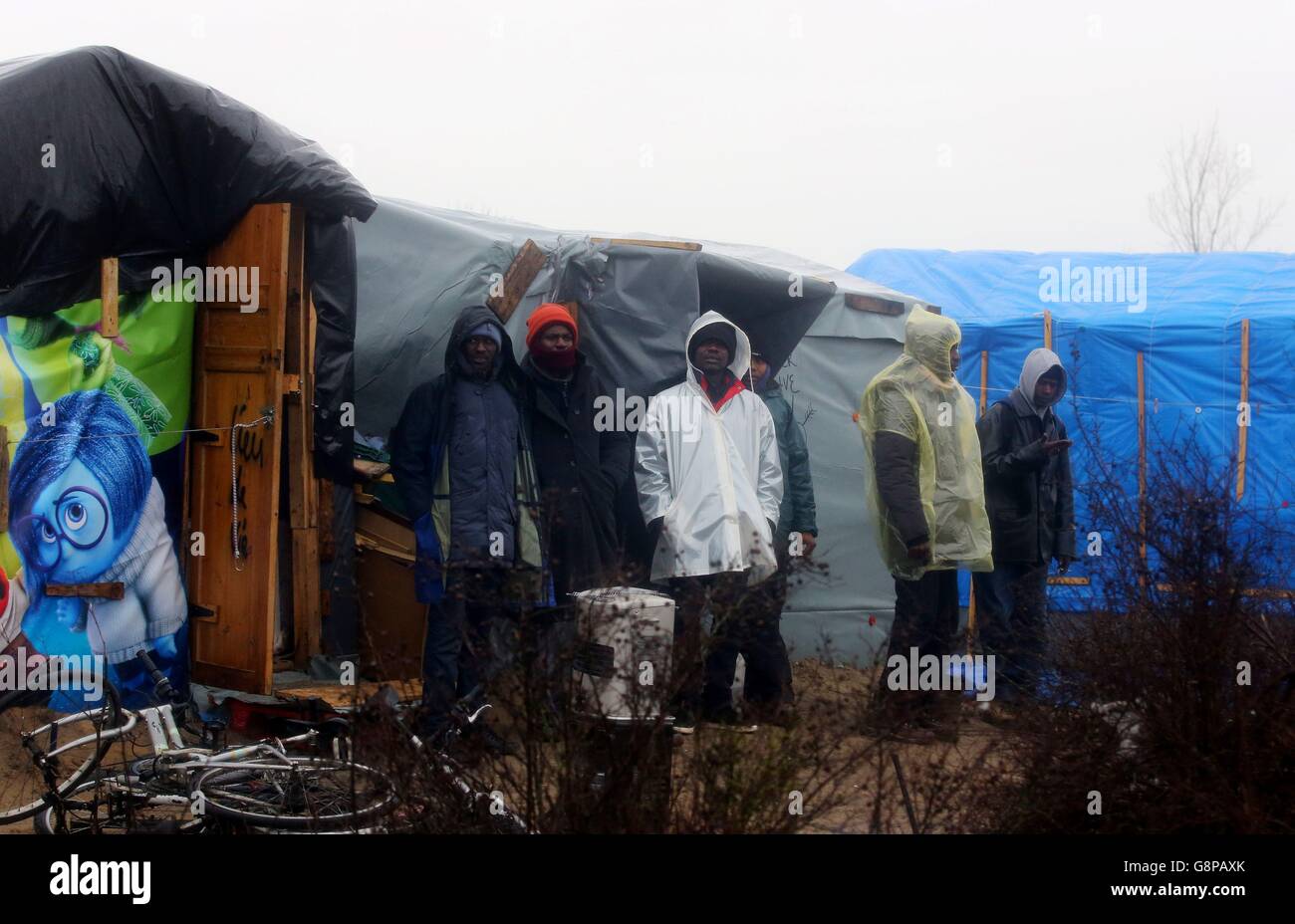 I migranti guardano da un baraccopoli nel campo di Calais, noto come la giungla, mentre la demolizione del campo è proseguita a Calais, in Francia. Foto Stock