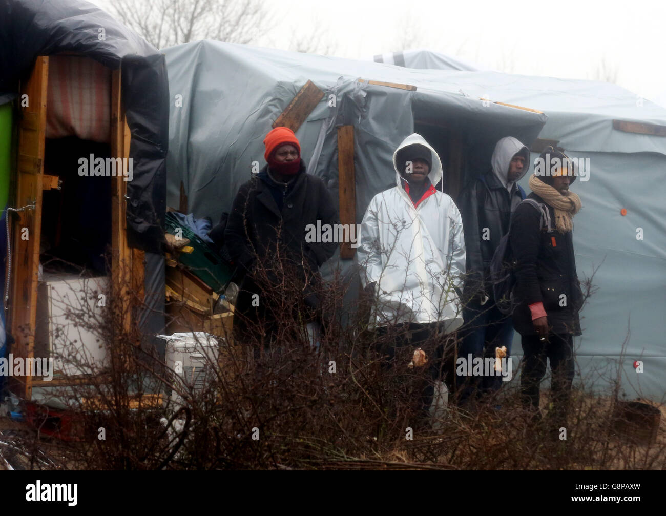 I migranti guardano da un baraccopoli nel campo di Calais, noto come la giungla, mentre la demolizione del campo è proseguita a Calais, in Francia. Foto Stock