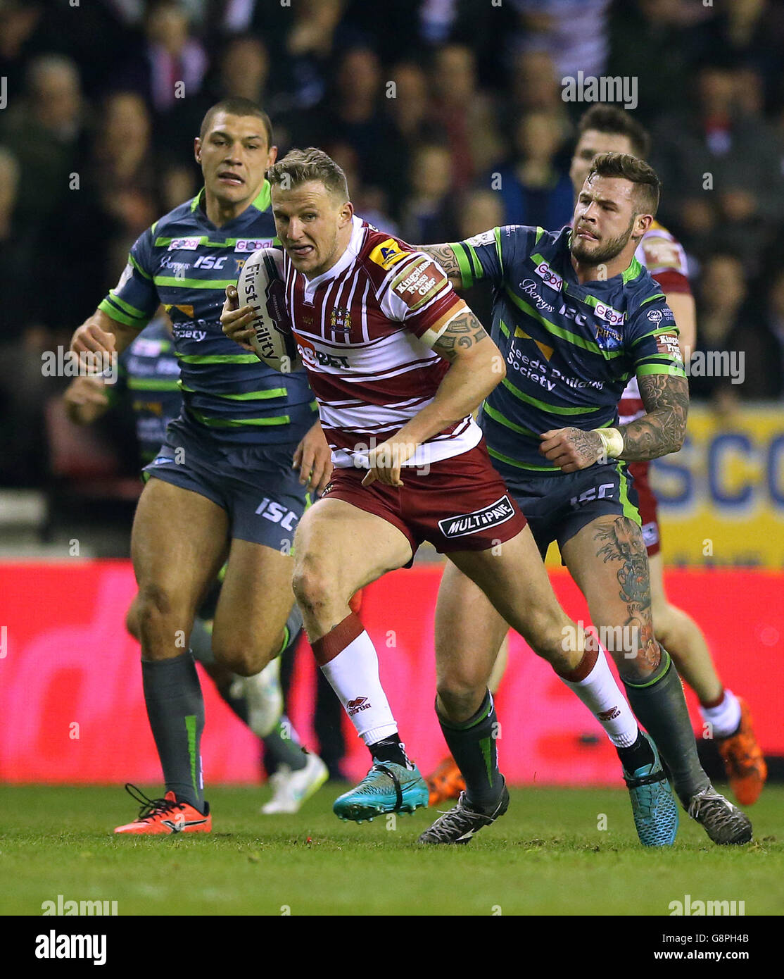 Il Dom Manfredi dei Warriors di Wigan si allontana da un attacco della Ryan Hall di Leeds Rhinos con Zak Hardaker (a destra), durante la prima partita della Utility Super League al DW Stadium, Wigan. Foto Stock