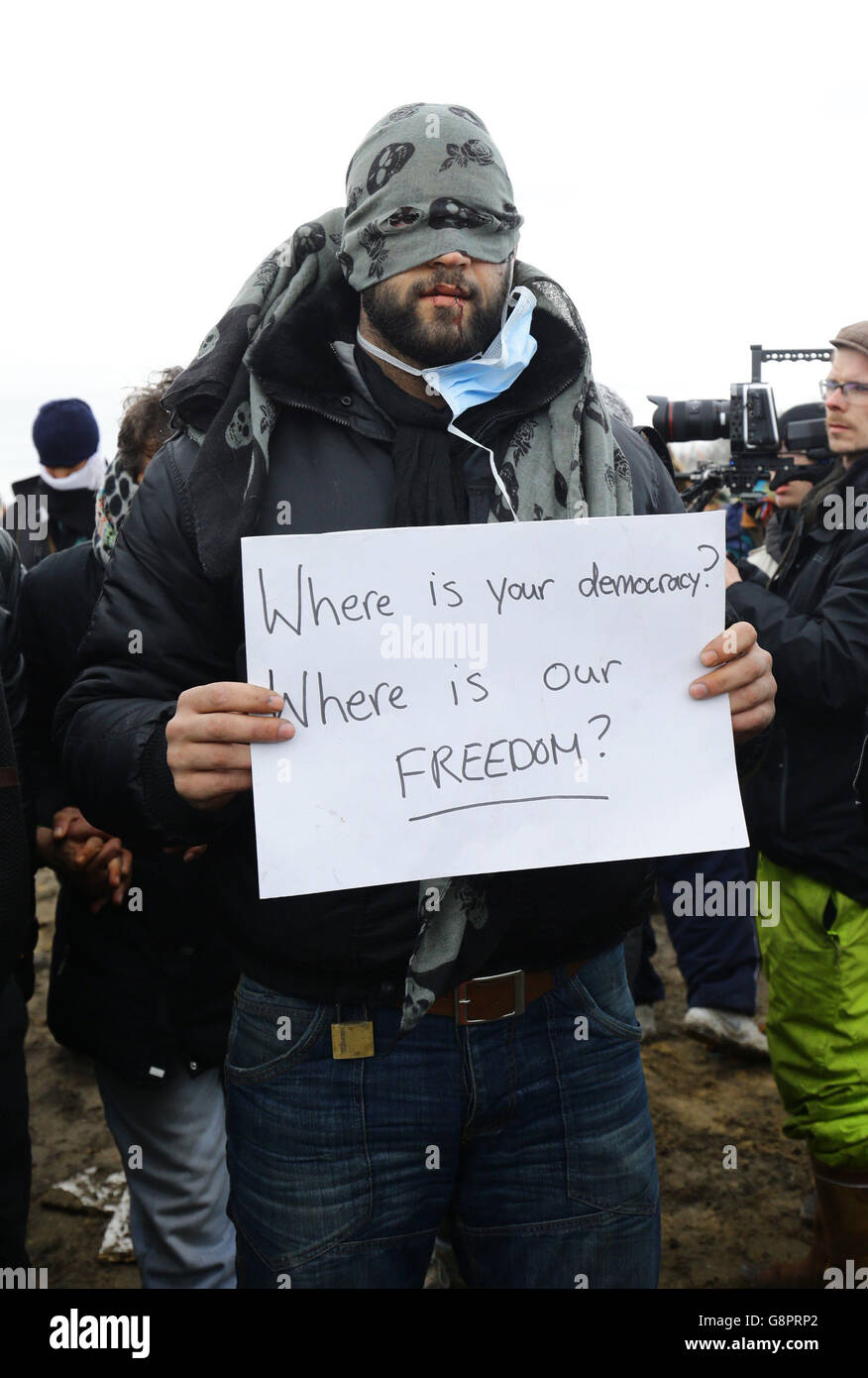 I migranti protestano mentre continuano le demolizioni nel campo migrante di Calais, noto come la giungla, nella Francia settentrionale. Foto Stock