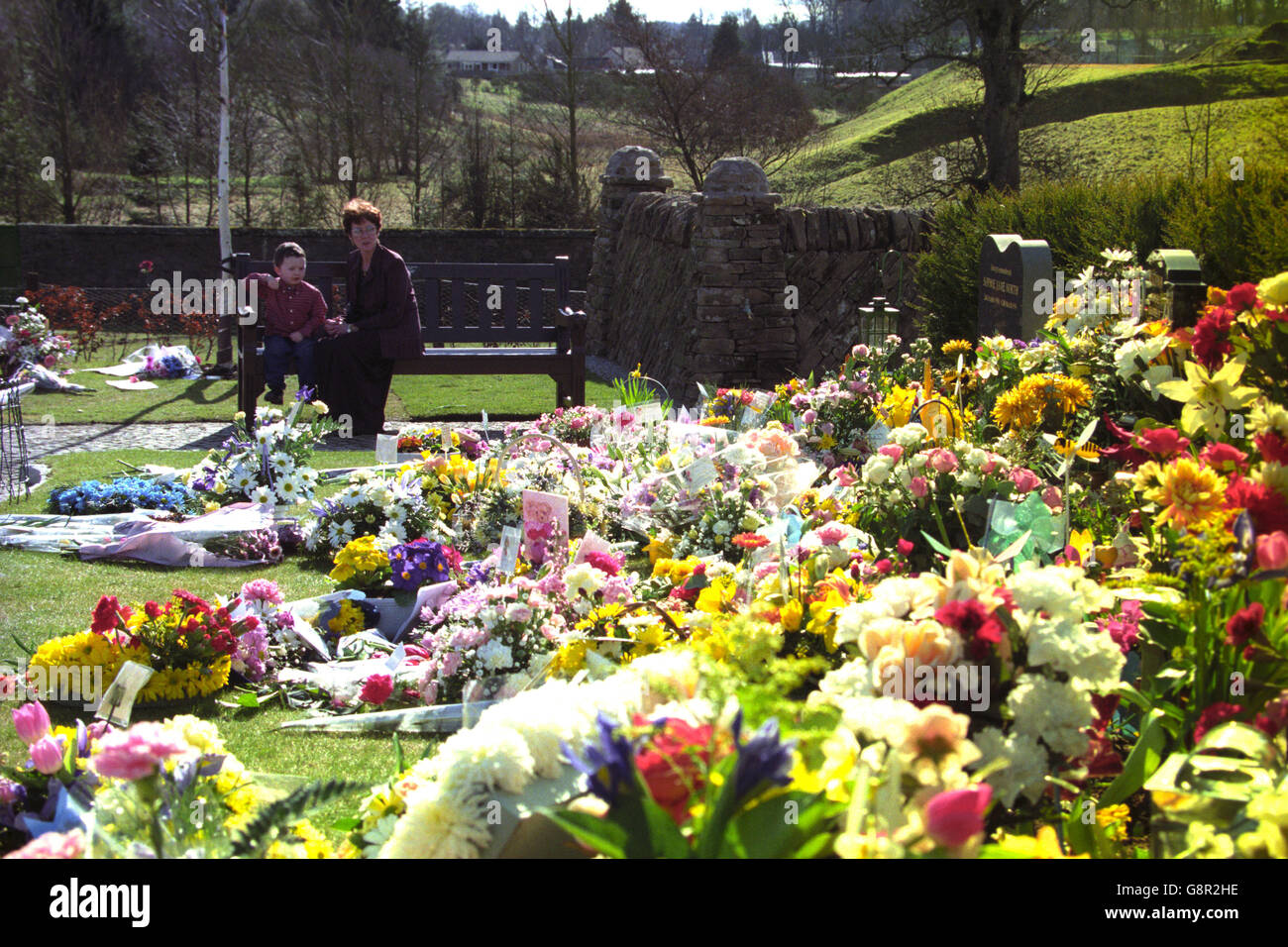 Connor Clydesdale, di tre anni, siede con la madre Irene nel Dunblane Memorial Garden. Segna il secondo anniversario del massacro scolastico di Dunblane. Foto Stock