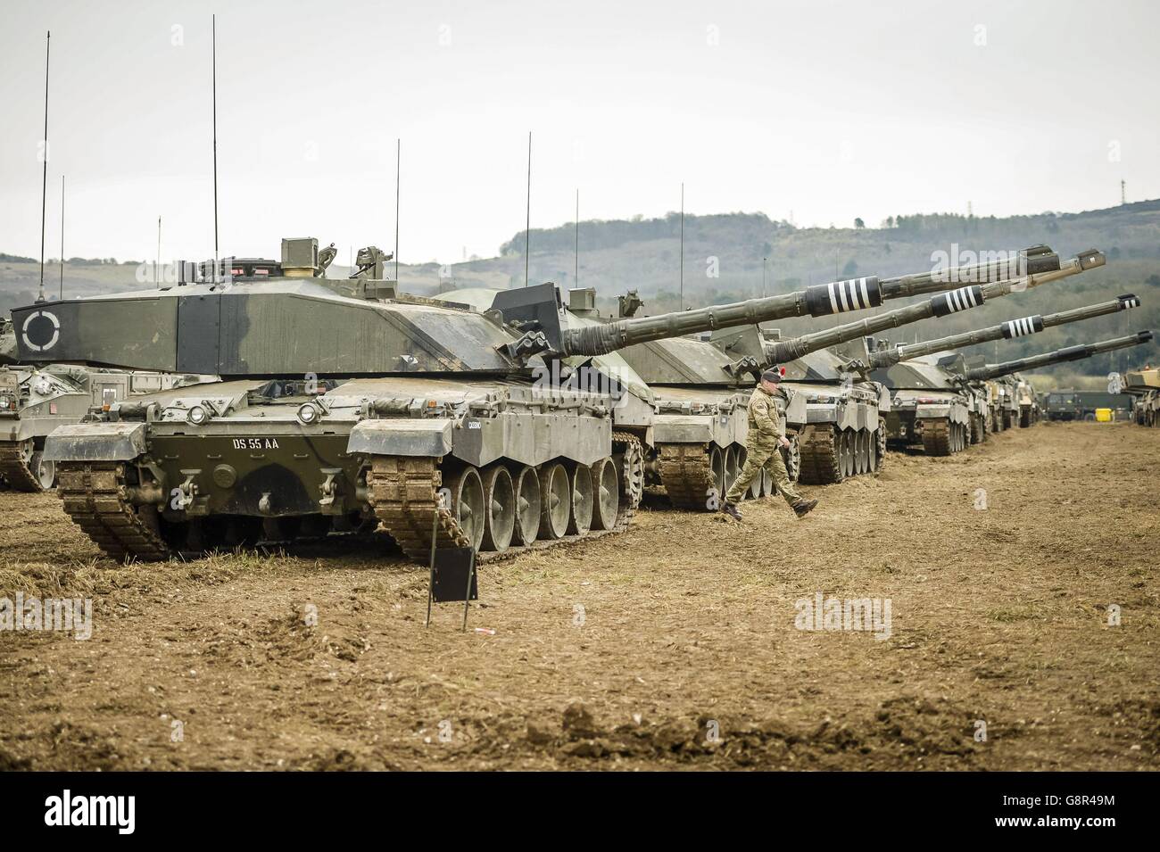 Un soldato oltrepassa una fila di carri armati da battaglia principali Challenger II, mentre la terza divisione (UK) prende parte all'esercizio TRACCIABILE 2016 a Salisbury Plain, Wiltshire, Progettato per testare la capacità della Lead Armwed Task Force (GAFI) della divisione di dispiegarsi dalle caserme attraverso un'area di sosta centralizzata, ai punti di imbarco aerei e marittimi. Foto Stock