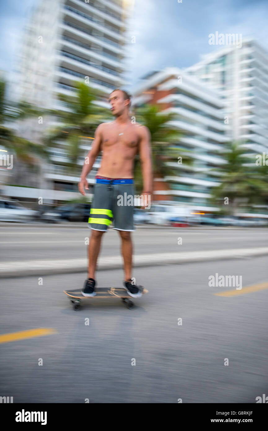 RIO DE JANEIRO - 6 Marzo 2016: il giovane brasiliano carioca uomo su skateboard si muove in una sfocatura di movimento lungo la strada sulla spiaggia. Foto Stock