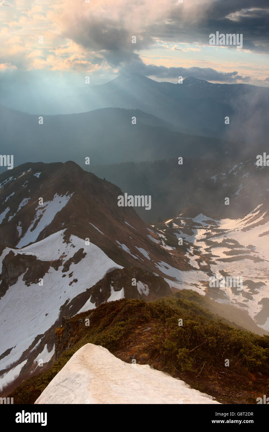 Inizio della primavera nelle montagne dei Carpazi, neve. luce attraverso le nuvole. L'illuminazione spot Foto Stock