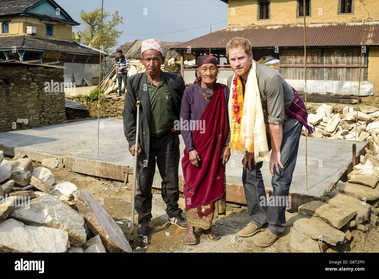 Il principe Harry pone per una foto con la signora Pakuli Gurung di 86 anni e il suo figlio maggiore (nome non dato) di fronte alle loro nuove fondamenta di casa a Bhir Kuna, mentre il principe visita il terremoto ha colpito il villaggio in Nepal e vede la sua ricostruzione. Foto Stock