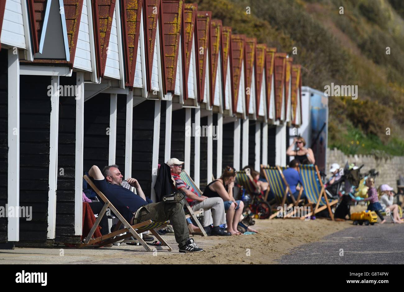 La gente gode il sole mentre si siedono fuori delle loro capanne sulla spiaggia di Bournemouth. Foto Stock