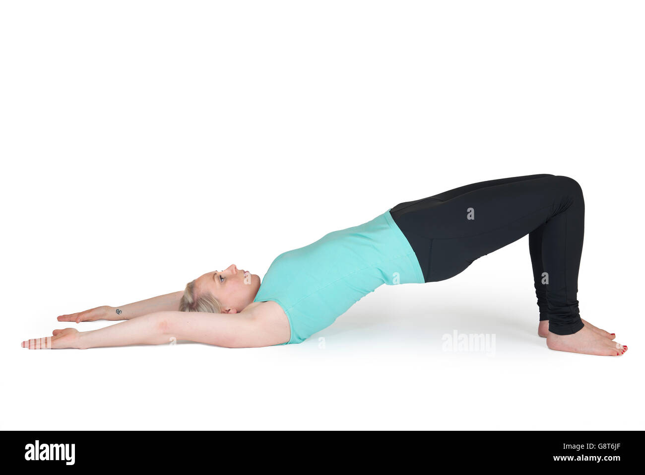 Corpo pieno vista di una giovane donna bionda in esercizi yoga 'supino con braccia tese sopra la testa' con contro backgrou bianco Foto Stock