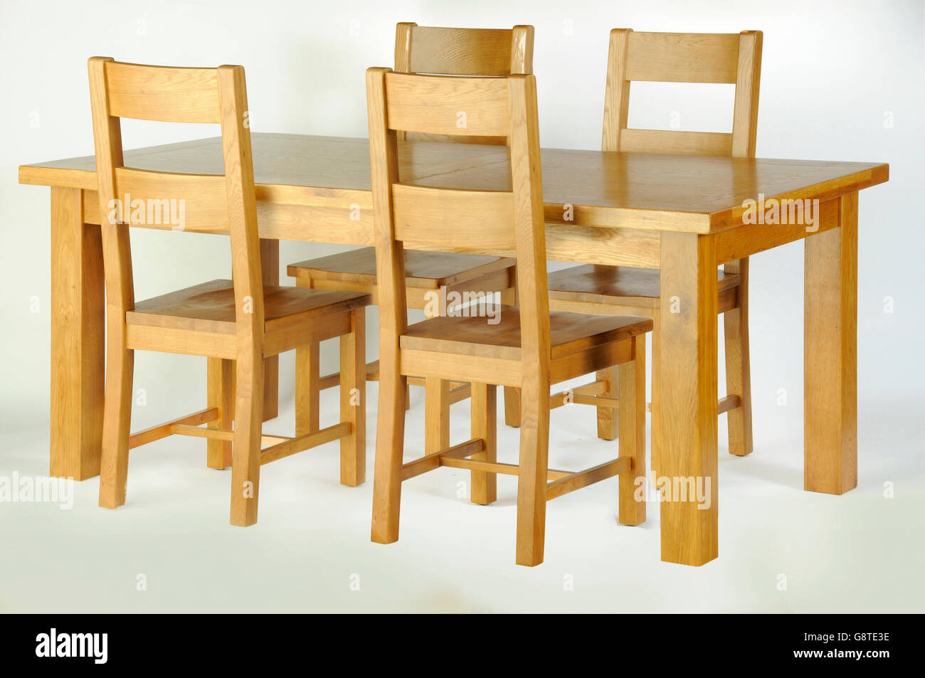 Un tavolo da pranzo in legno e quattro sedie di legno su sfondo bianco Foto Stock