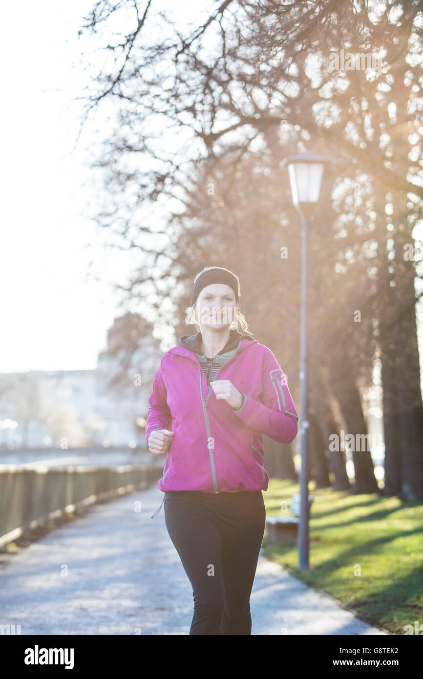 Donna in abiti sportivi jogging sul sentiero in città Foto Stock