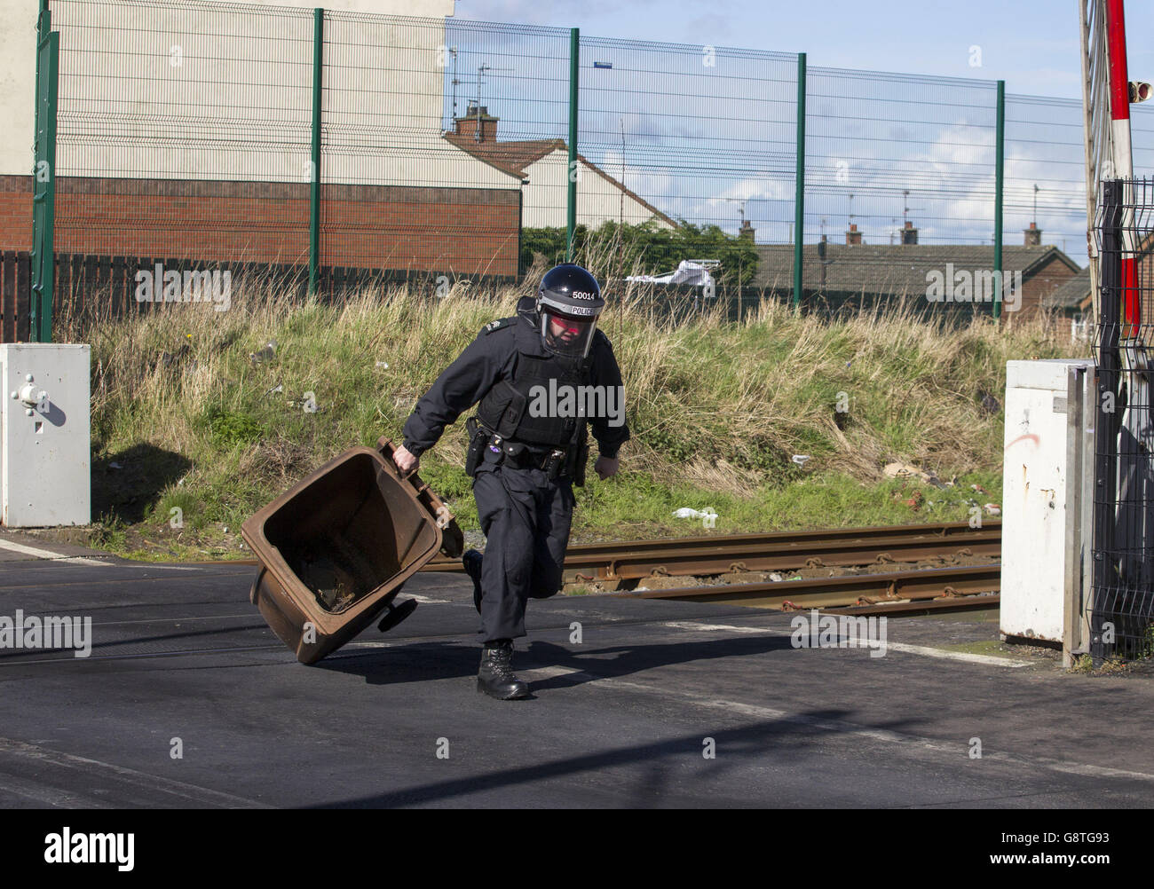 Un ufficiale PSNI sulla scena in cui una pattina è stato messo in fuoco e lasciato sulla linea ferroviaria di Dublino a Belfast, il disturbo arriva ore dopo l'ordine fedele protestante i ragazzi apprendisti di Derry sfilato attraverso Lurgan in Irlanda del Nord. Foto Stock