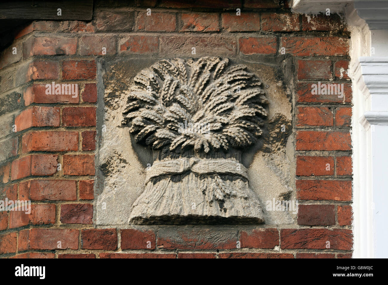 Un'immagine tradizionale di un covone di grano scavate nella pietra su un edificio in Steyning, West Sussex. Foto Stock