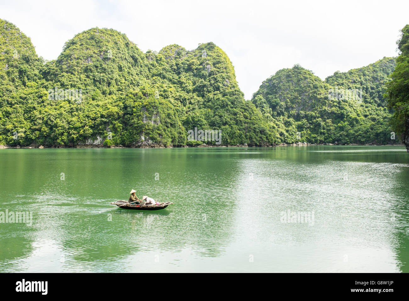Piccola barca da pesca con pescatori irriconoscibile indossando il tradizionale vietnamita cappelli a vela in Cat Ba parco nazionale Foto Stock