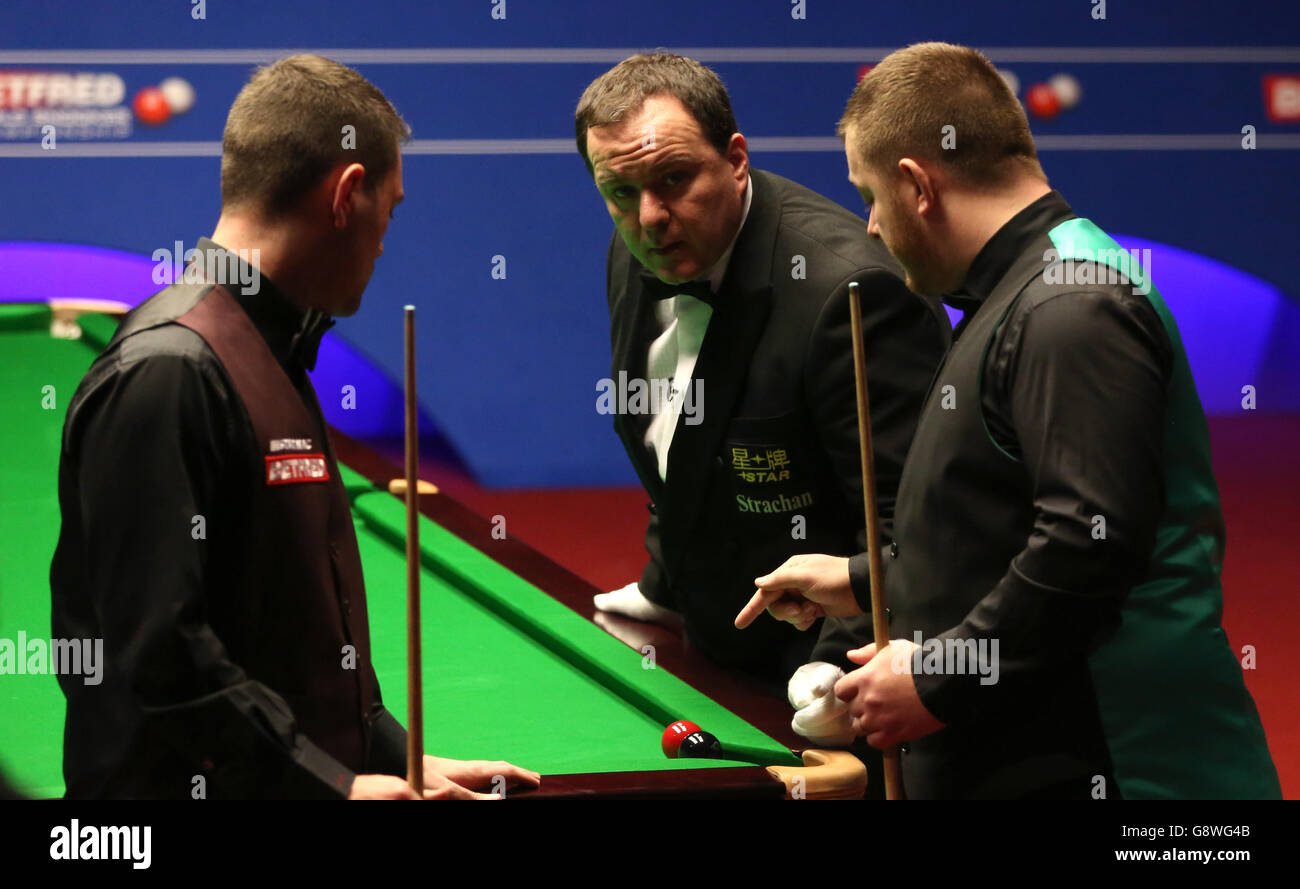 Mitchell Mann (a sinistra) e Mark Allen discutono la posizione della palla rossa e nera con l'arbitro Colin Humphries durante il quarto giorno dei Campionati Mondiali di Snooker Betfred al Crucible Theatre di Sheffield. Foto Stock