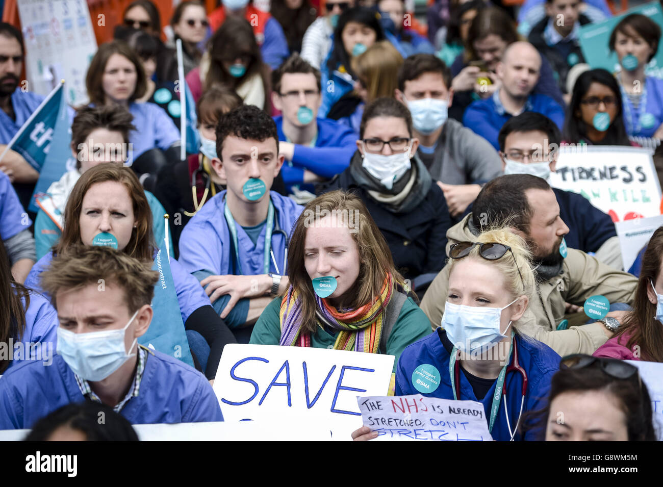 I medici e i sostenitori junior degli scioperi BMA indossano maschere facciali e adesivi sulla bocca mentre si siedono in una protesta silenziosa fuori dall'infermeria reale di Bristol il secondo giorno dell'azione di sciopero totale durante la quale i medici in formazione non forniranno assistenza di emergenza per i pazienti. Foto Stock