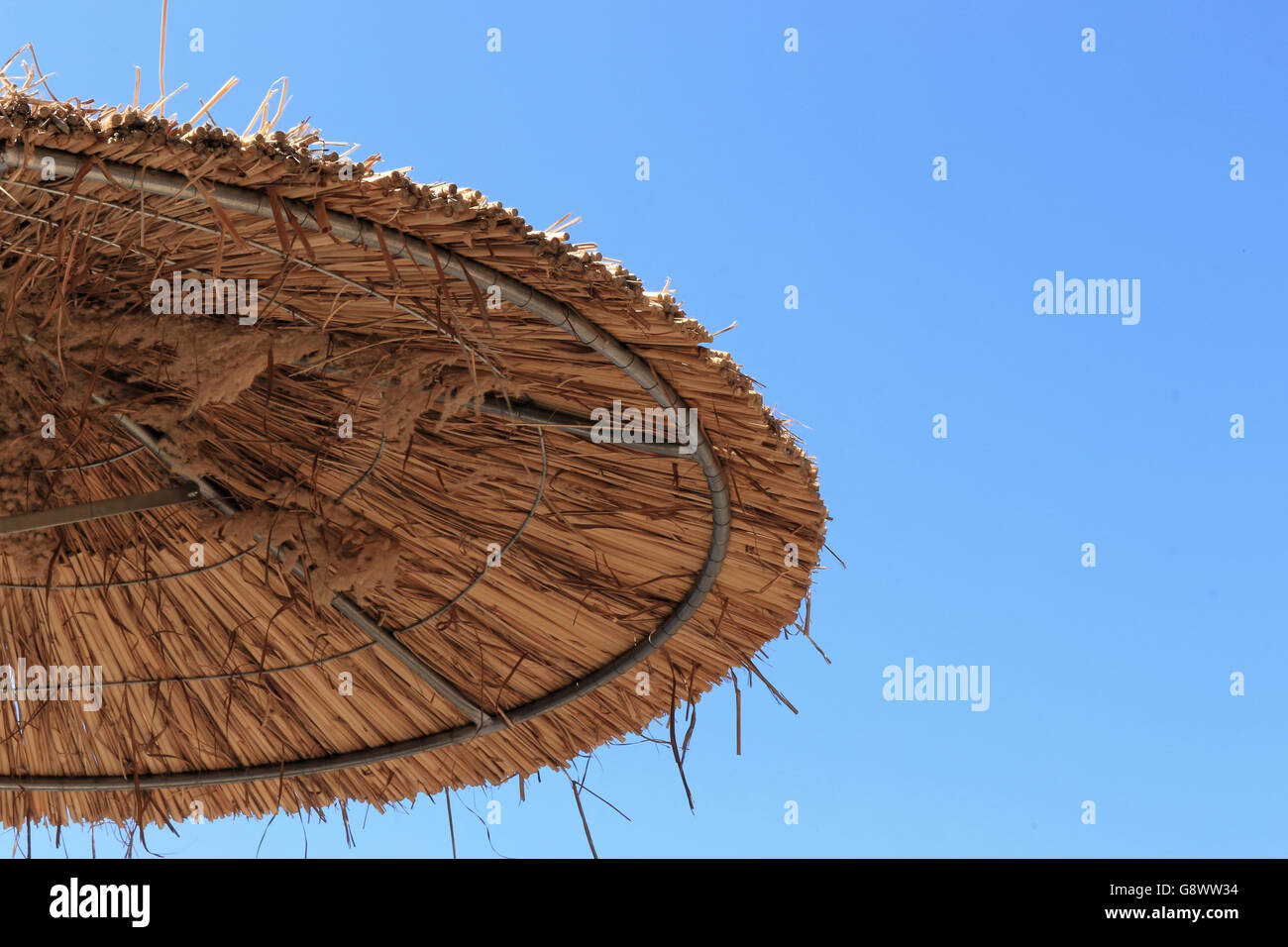 Con il tetto di paglia ombrellone sul cielo azzurro sfondo Foto Stock