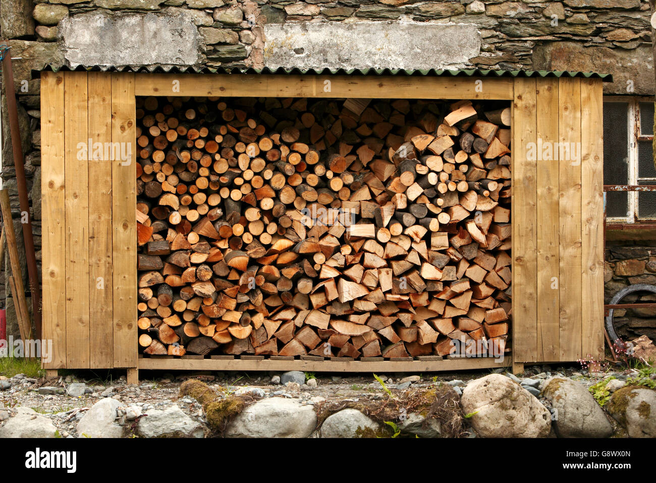Aprire tettoia in legno negozio log riempiti con un trito di registri, pronto per l'inverno. Cumbria Lakeland Lake District. Regno Unito Foto Stock