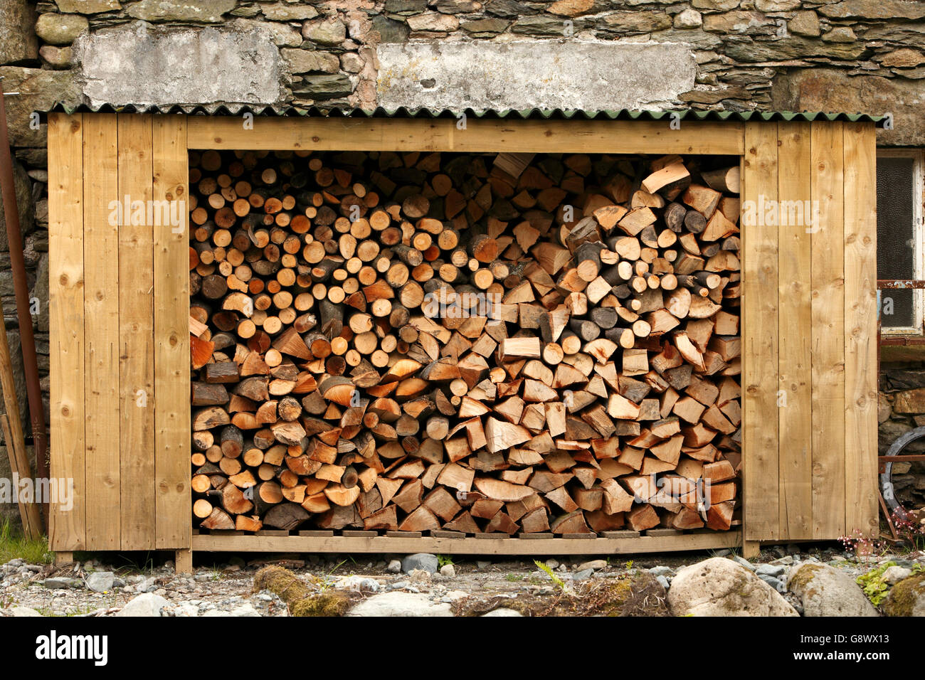 Aprire tettoia in legno negozio log riempiti con un trito di registri, pronto per l'inverno. Cumbria Lakeland Lake District. Regno Unito Foto Stock