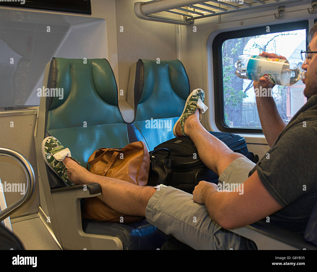 Un uomo rude tenuto troppo in molti posti a sedere su un treno. Foto Stock