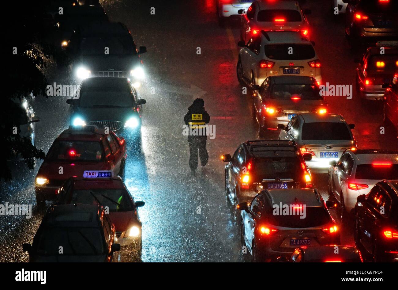 Shenyang, cinese della provincia di Liaoning. Il 30 giugno, 2016. Un poliziotto dirige il traffico sotto la pioggia in Hunnan distretto di Shenyang, città capitale del nord-est della Cina di Provincia di Liaoning, 30 giugno 2016. La locale Autorità Meteorologica ha emesso un avviso di colore arancione per temporali giovedì. Credito: Yang Qing/Xinhua/Alamy Live News Foto Stock