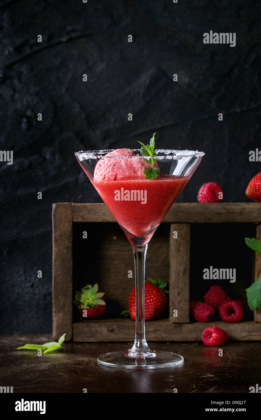 Confetti bicchiere da cocktail di fragole dessert con sorbetto, servita su sfondo scuro con fragole, lamponi e menta behi Foto Stock