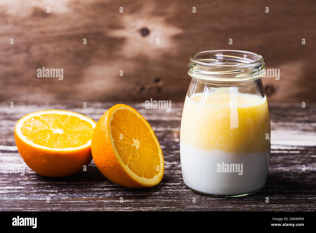 Deliziosa casa arancione organico frullati in un vasetto di vetro con un fresco e fettine di arancia sul tavolo di legno Foto Stock