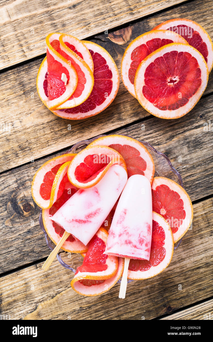 Gelato fatto in casa con succo di pompelmo fresco e yogurt congelato sul tavolo di legno, vista dall'alto Foto Stock