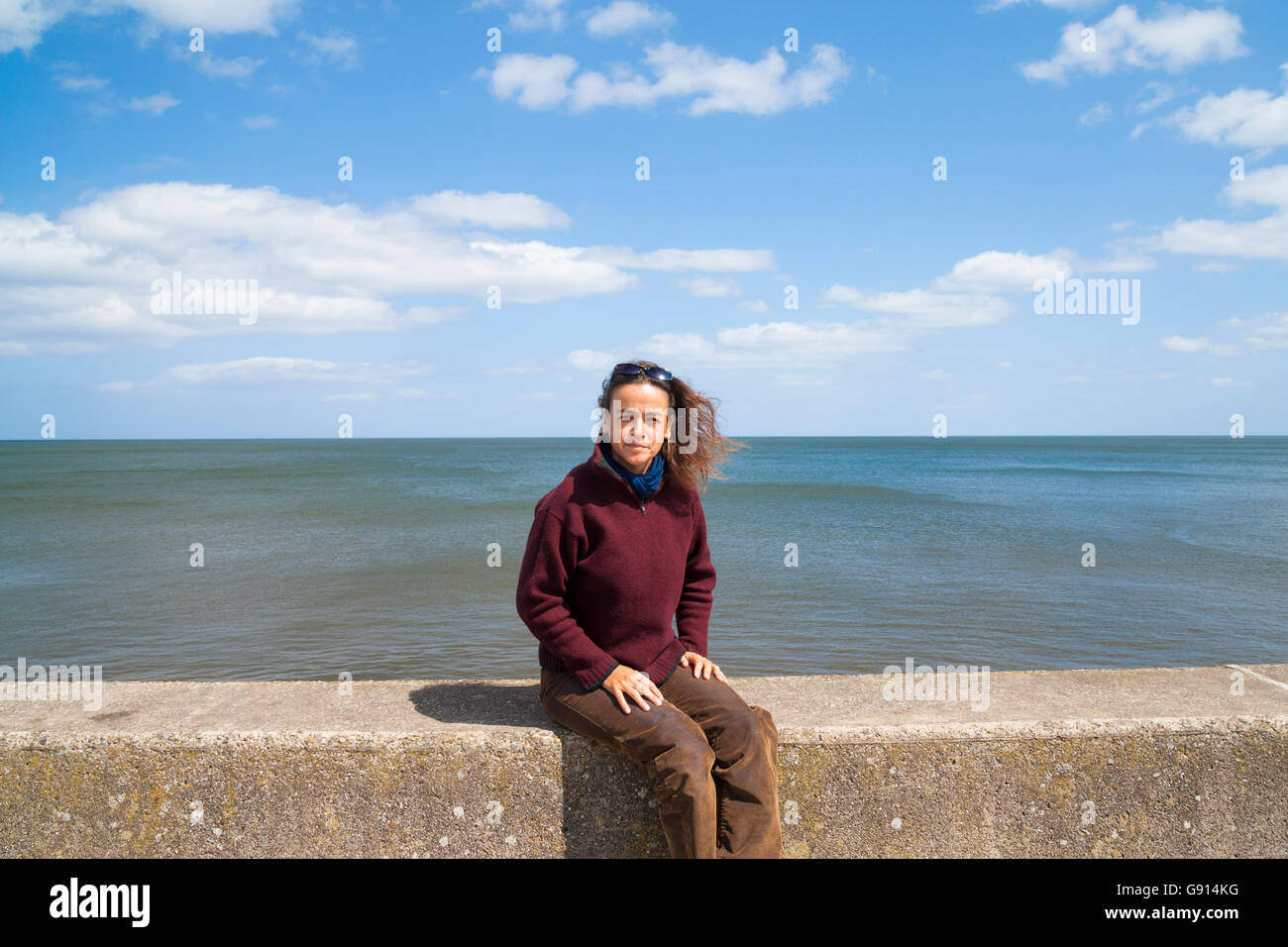 Lo spagnolo donna seduta sulla parete del mare a Sandsend, North Yorkshire, Inghilterra. Regno Unito Foto Stock