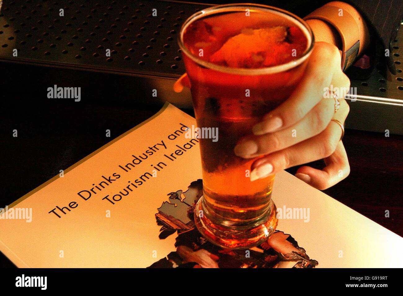 Un bevitore mette un bicchiere di lager su una copia di un rapporto dell'economista della Dublin City University Tony Foley a Boswells Hotel, nel centro di Dublino. Il rapporto ha esaminato il legame tra l'industria delle bevande e il turismo in Irlanda e ha rivelato che i produttori e i fornitori hanno fatto un quarto della sponsorizzazione per i festival del paese e che l'equivalente di 80,000 posti di lavoro a tempo pieno è rappresentato dal settore. Foto Stock