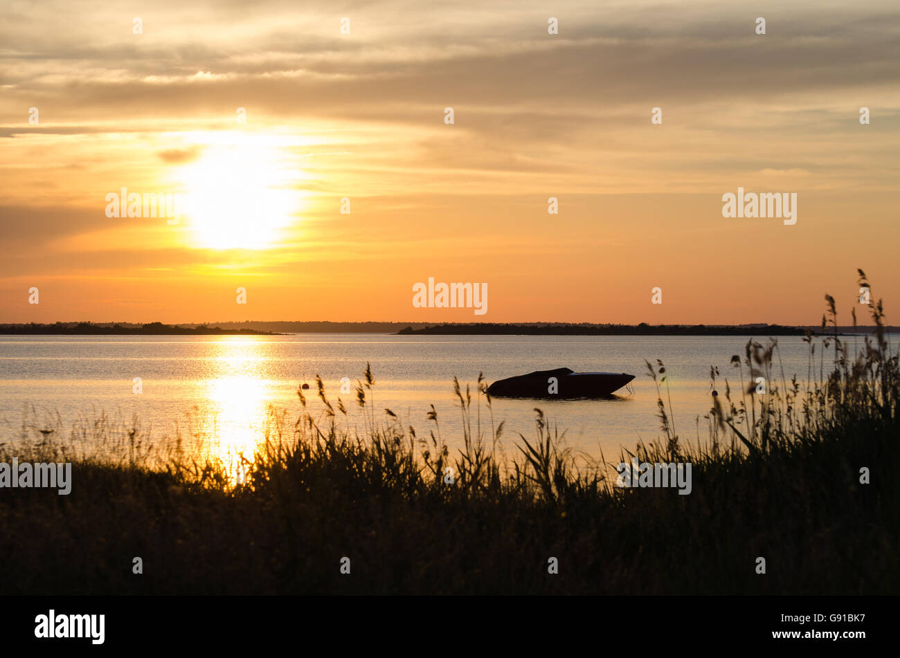 Silhouette di barca dal tramonto con riflessi dorati in acqua Foto Stock