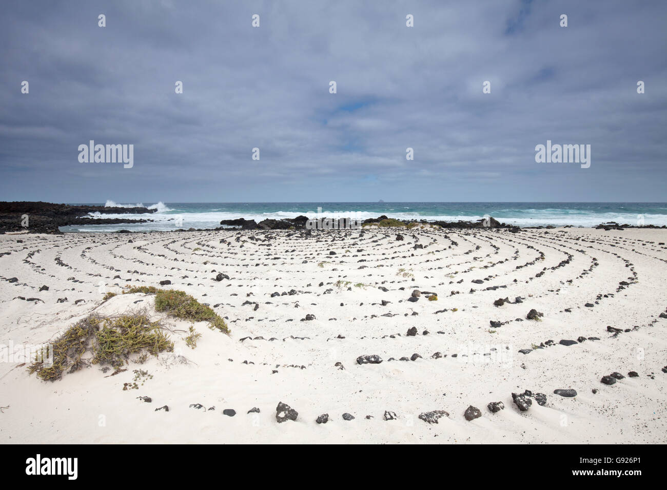 Spiaggia di sabbia bianca e la scultura in pietra vicino a Orzola nord di Lanzarote, Isole Canarie Foto Stock