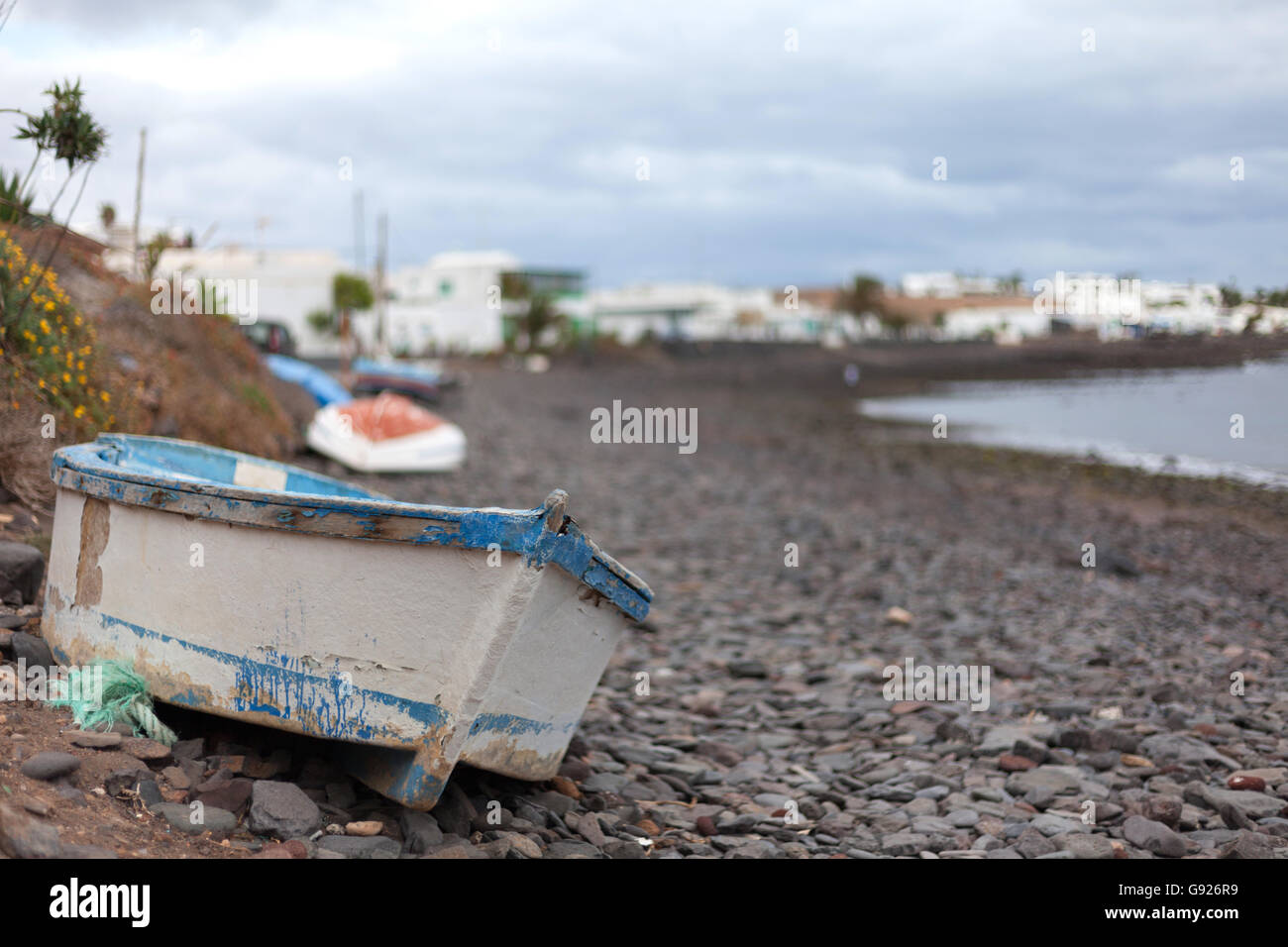 Playa barca Quemada sulla spiaggia sassosa guardando verso il piccolo villaggio di pescatori, Lanzarote Foto Stock