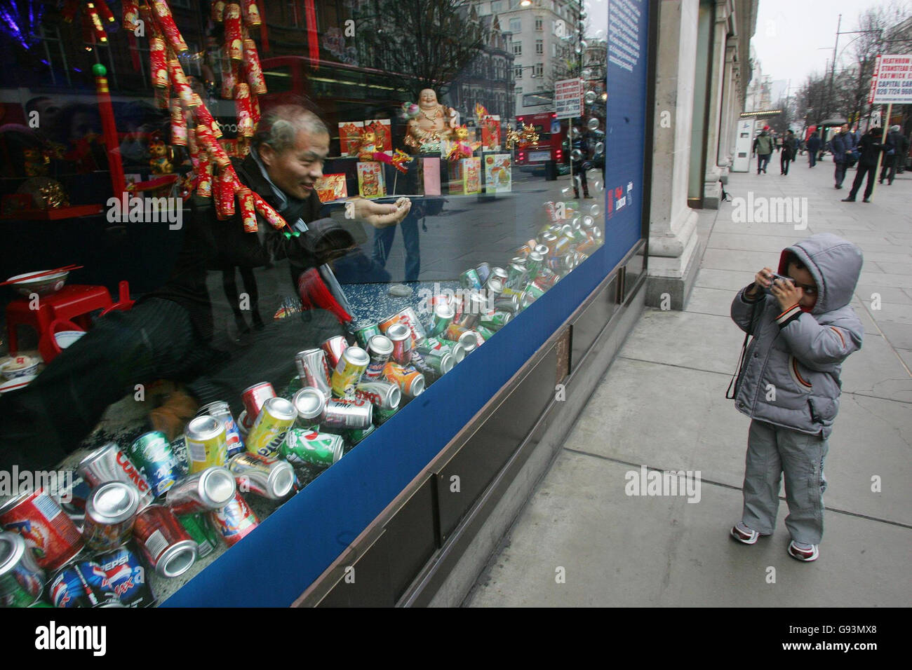 L'artista cinese Wang Qingsong siede nella vetrina di Selfridges su Oxford Street, nel centro di Londra, lunedì 23 gennaio 2006. Wang ha creato un'installazione attraverso l'intera serie di vetrine Selfridges front shop dal titolo `Follow Me’, che impiega motivi e simboli della cultura popolare ispirati all'appetito globale per lo shopping. PREMERE ASSOCIAZIONE foto. Il credito fotografico dovrebbe essere: Geoff Caddick/PA Foto Stock