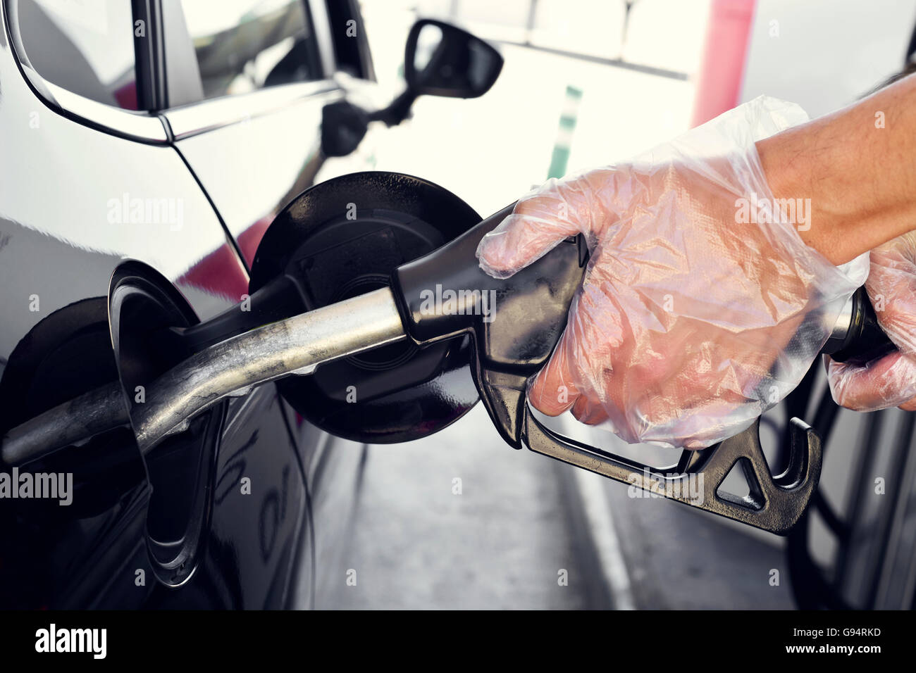 Primo piano di un giovane uomo caucasico di riempimento del serbatoio del carburante di un automobile Foto Stock