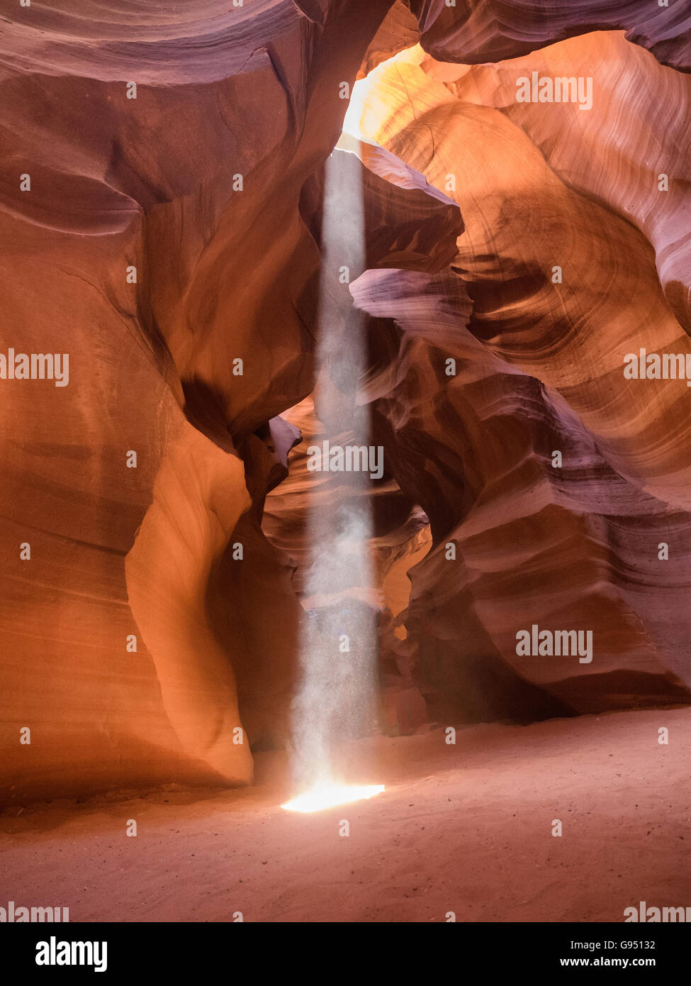 Il mezzogiorno in rosso-arancione Antelope Canyon. Un sottile raggio di sole illumina il fondo sabbioso del canyon Foto Stock