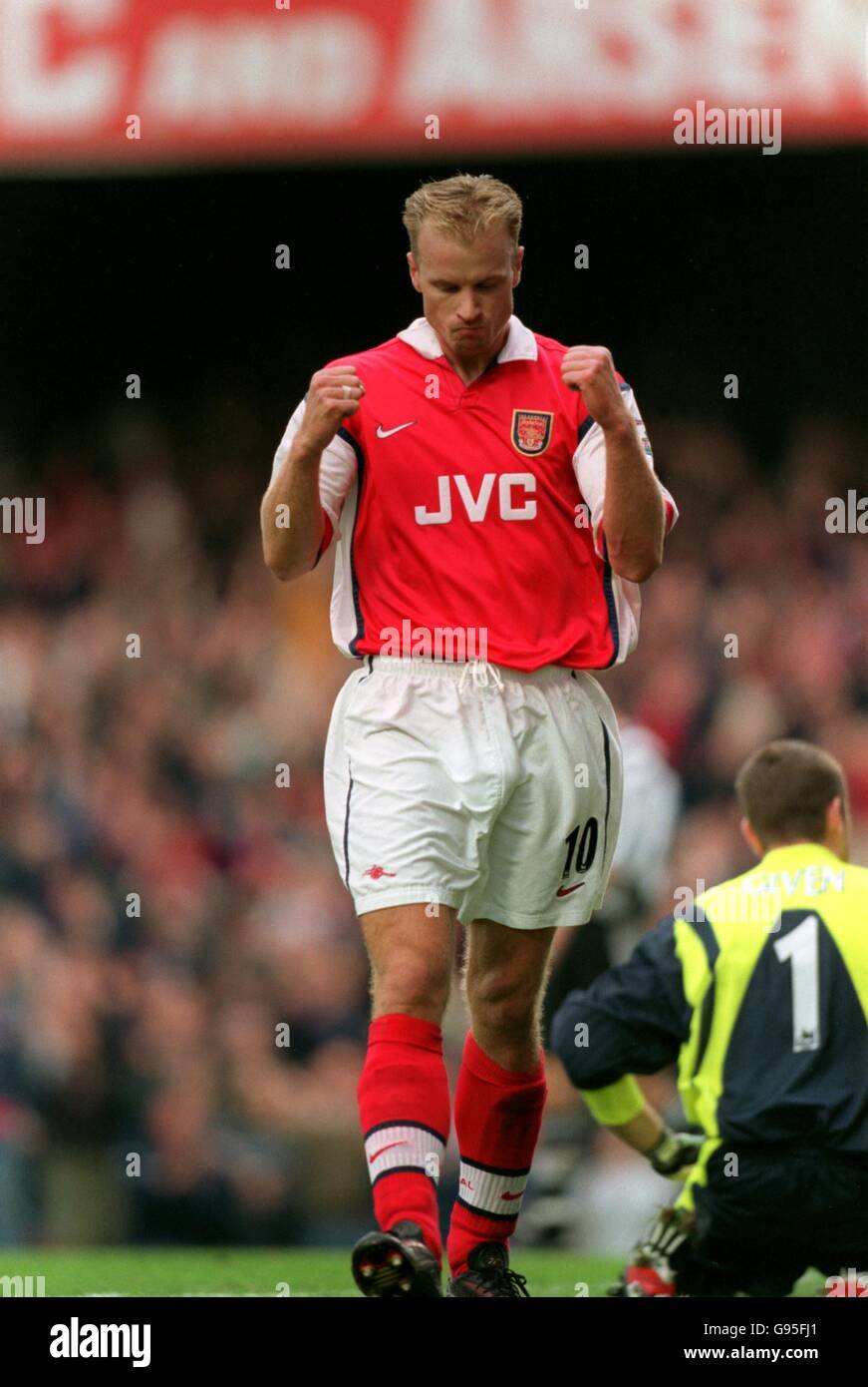 Dennis Bergkamp of Arsenal celebra il primo goal del gioco come il portiere del Newcastle United Shay Gaid (a destra) è in ginocchio nella disperazione Foto Stock