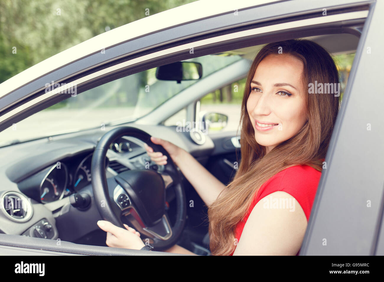Giovane donna felice alla guida di una nuova o auto a noleggio. Noleggio auto sfondo Foto Stock