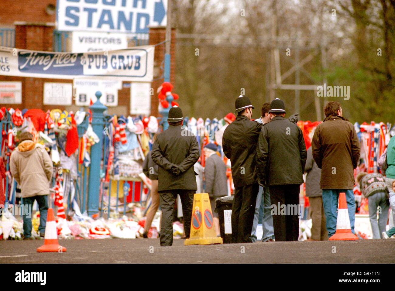 I poliziotti si trovano all'esterno della Lepping Lane End del terreno di Hillsborough, mentre i fiori si accumulano in memoria dei fan che sono morti. Foto Stock