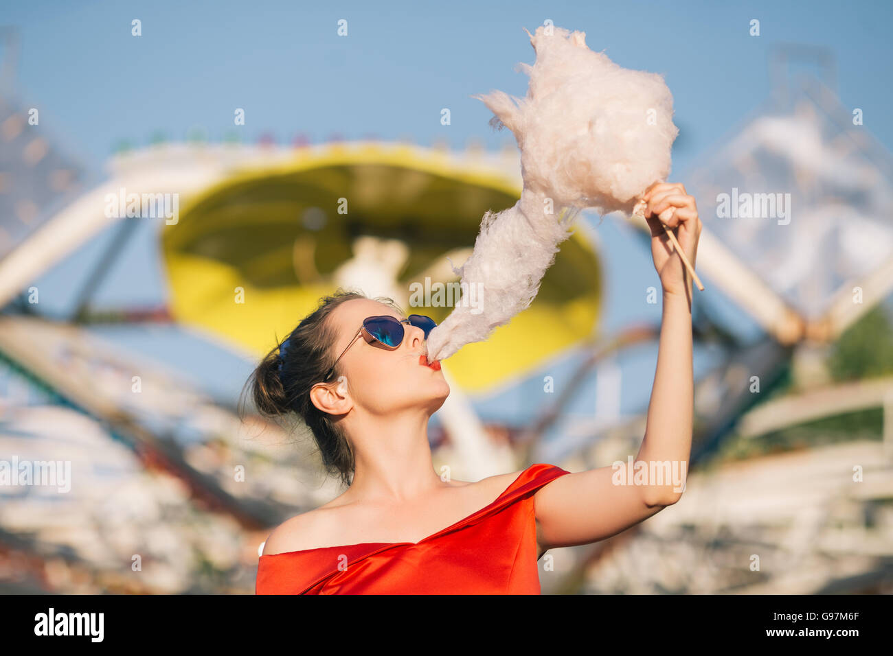 Ragazza di mangiare il cotone candy in luna park Foto Stock