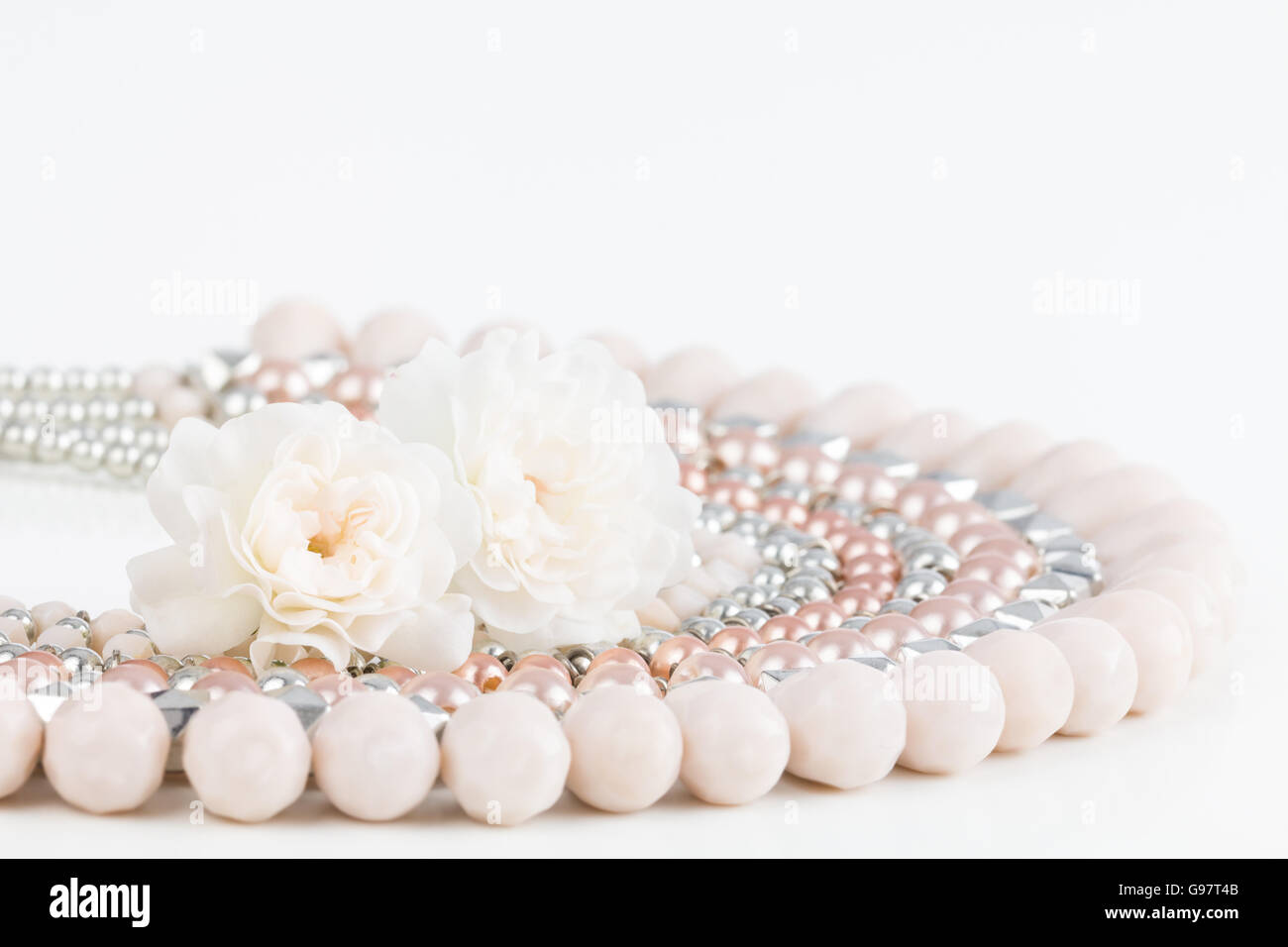 Close up di rosa pastello un nastro di perline collana con abbinamento di Rosa Rose in miniatura. Foto Stock