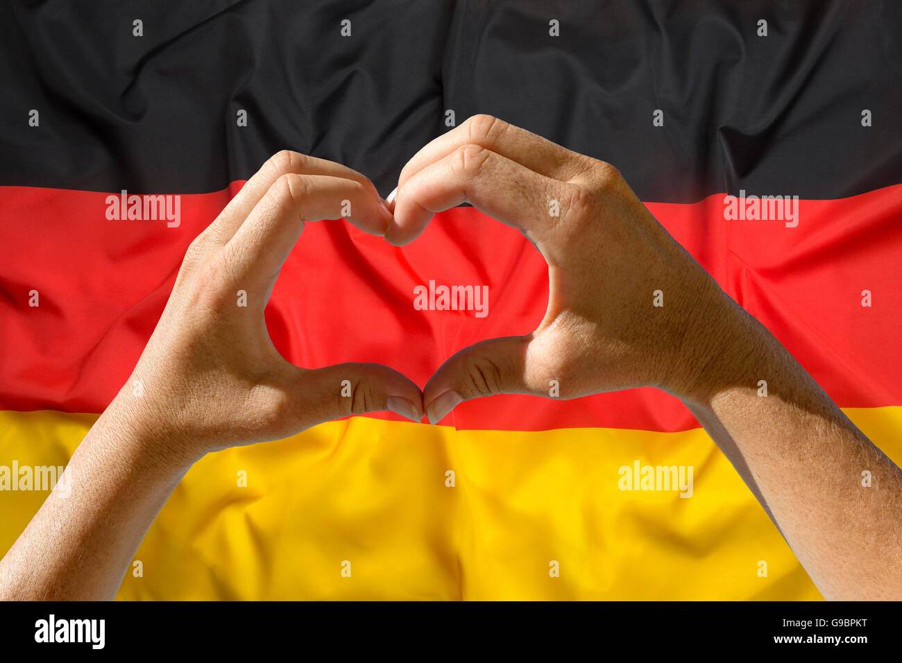 Mani femminili il simbolo del cuore con la bandiera della Germania in background Foto Stock