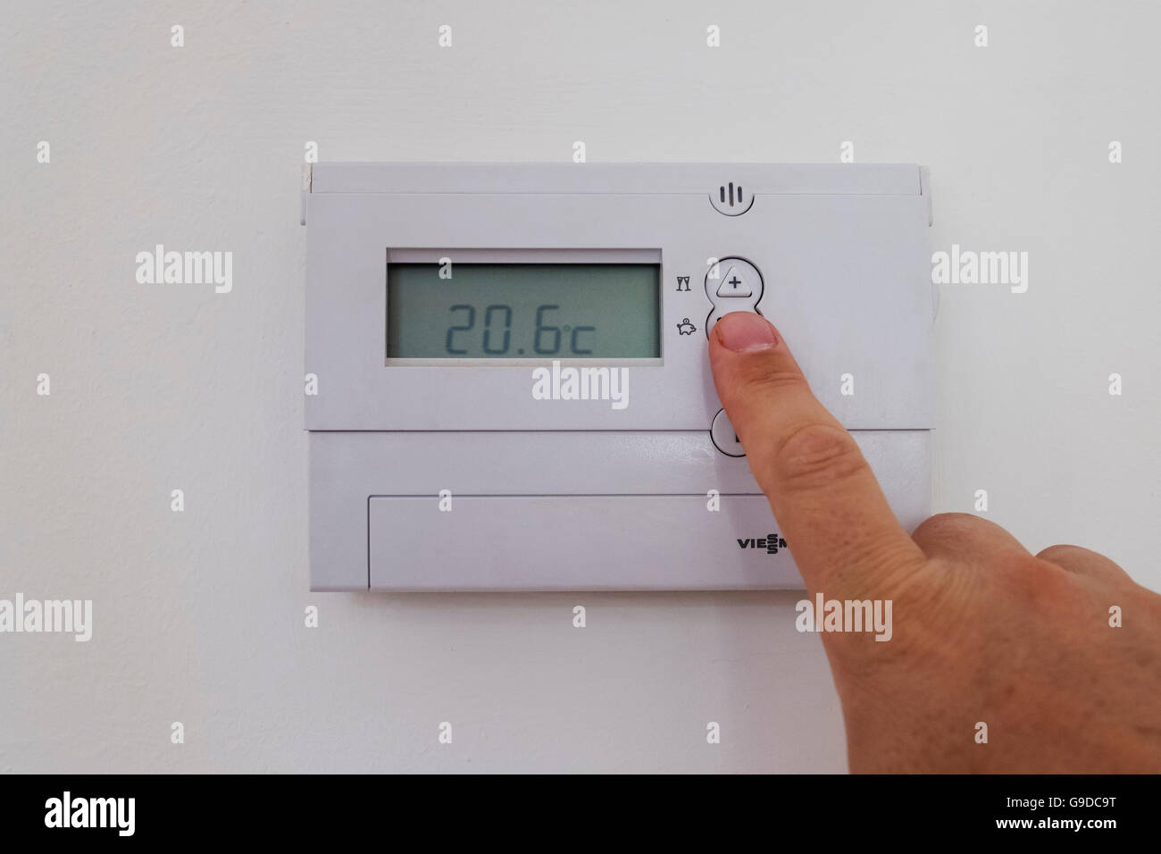 Uomo di casa di regolazione riscaldamento centrale il termostato a una temperatura più bassa e di risparmiare energia e denaro. Foto Stock
