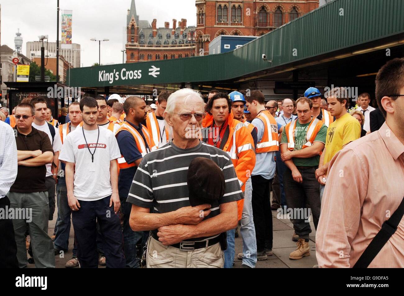 La scena al di fuori alla stazione ferroviaria di Kings Cross a Londra, come centinaia di office e lavoratori edili stand per un cittadino di due minuti di silenzio, sul primo anniversario degli attentati terroristici a Londra il sistema di trasporto. Foto Stock