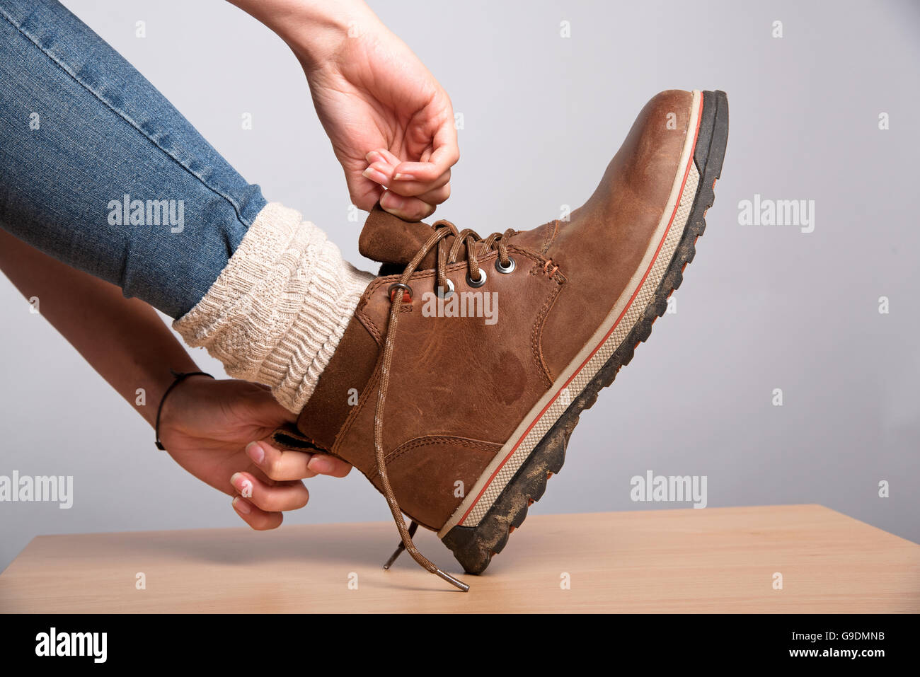 Donna di mettere le mani su un marrone walking boot Foto Stock