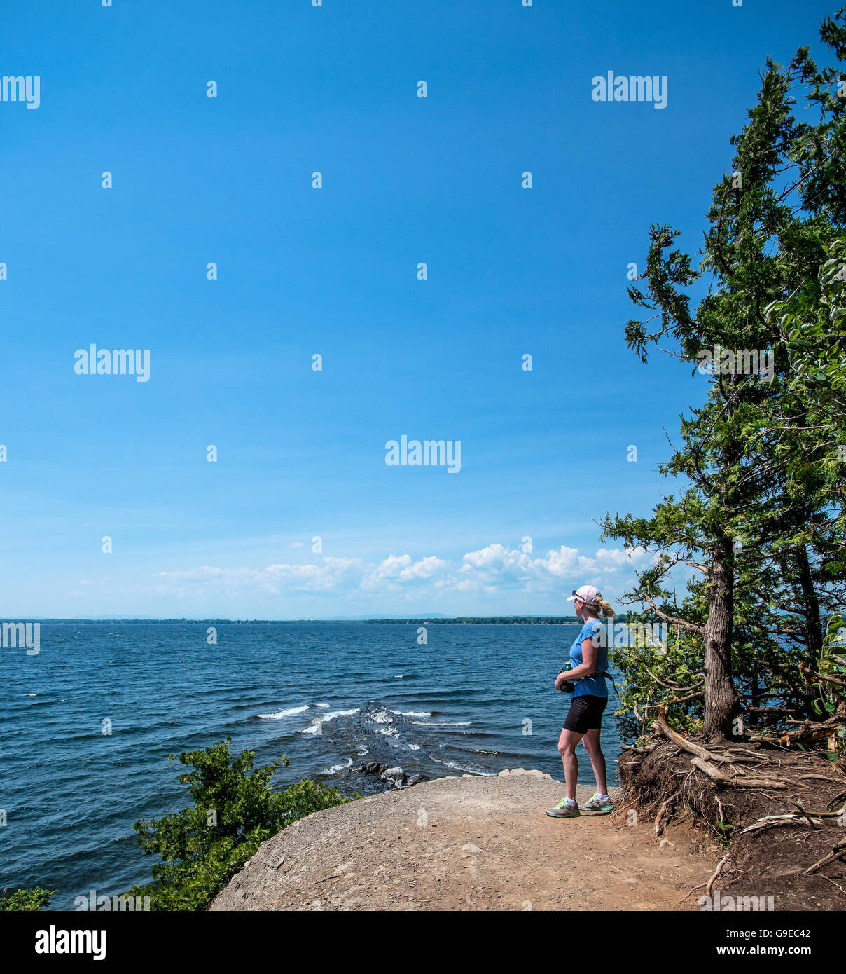 Donna che guarda fuori attraverso il lago Champlain da un rocky point Foto Stock