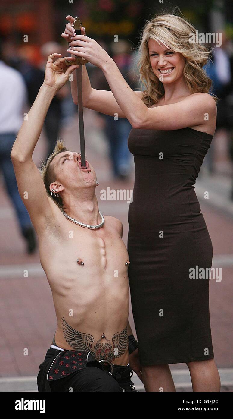 Top modello irlandese Jenny Lee rimuove una spada dalla bocca di un artista noto come Australian Space Cowboy, nel centro della città di Dublino, per lanciare la prima mai street performance nel campionato del mondo che si terrà il 5 agosto e il 6° al Merrion Square nella città. Foto Stock